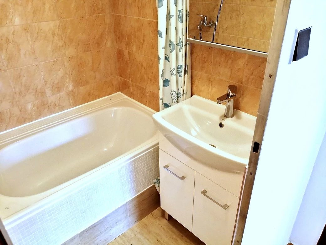 Koupelna investičního bytu po úpravách – nová vana a umyvadlo